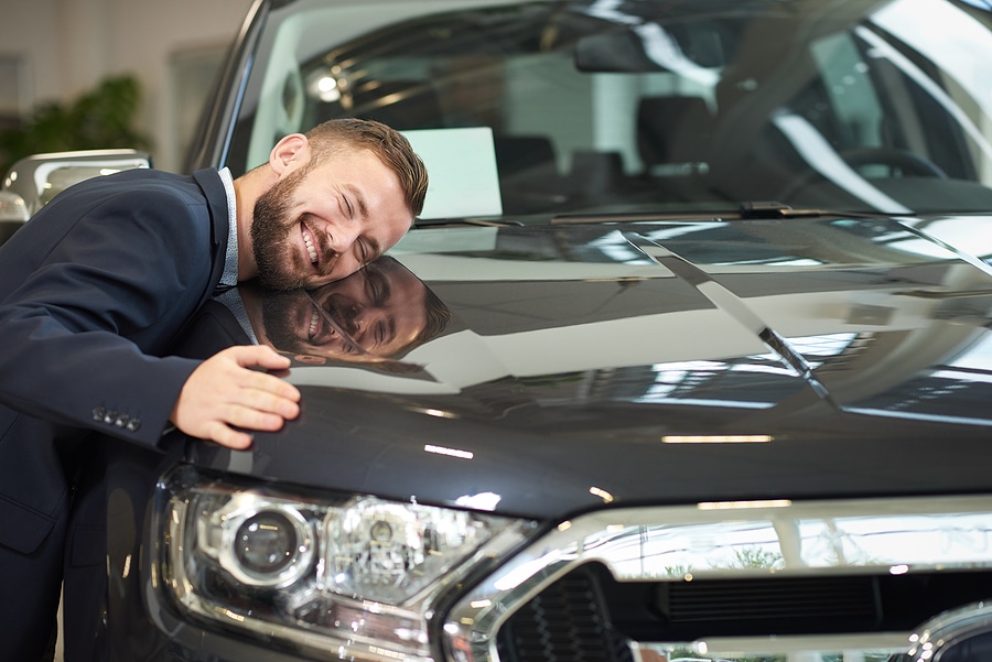 Happy owner of restored automobile smiling with closed eyes.